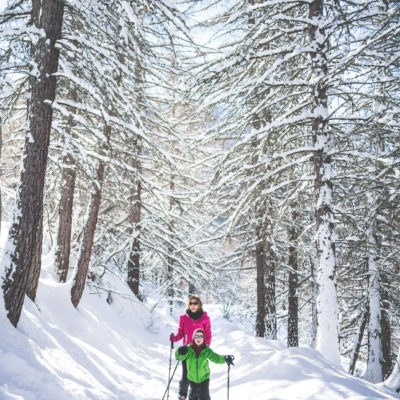 Woman snowshoeing in a sunny day with her son
