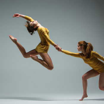 The two modern ballet dancers dancing on gray background